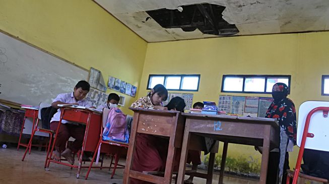 Siswa SDN 01 Alasbayur belajar di ruang kelas yang rusak di Desa Alasbayur, Mlandingan, Situbondo, Jawa Timur, Rabu (15/12/2021). ANTARA FOTO/Seno