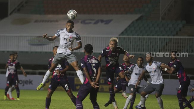 Penyerang Persis Solo Rifaldi Bawuo berusaha mencetak gol melalui sundulan selama pertandingan grup X babak 8 besar Liga 2 antara RANS Cilegon FC melawan Persis Solo di Stadion Pakansari, Bogor, Jawa Barat, Rabu (15/12/2021). [Suara.com/Angga Budhiyanto]