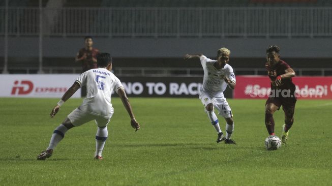 Gelandang Sriwijaya FC Hari Habrian (kanan) berusaha melewati gelandang Persiba Balikpapan C. Huwae (tengah) selama pertandingan grup X babak 8 besar Liga 2 antara Sriwijaya FC melawan Persiba Balikpapan di Stadion Pakansari, Bogor, Jawa Barat, Rabu (15/12/2021). [Suara.com/Angga Budhiyanto]