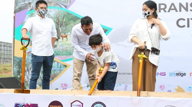 Presenter Raffi Ahmad membantu putranya, Rafathar untuk melempar tanah saat acara Groundbreaking RANS Carnival Zoo di Pantai Indah Kapuk 2, Banten, Jumat (17/12/2021). [Suara.com/Alfian Winanto]