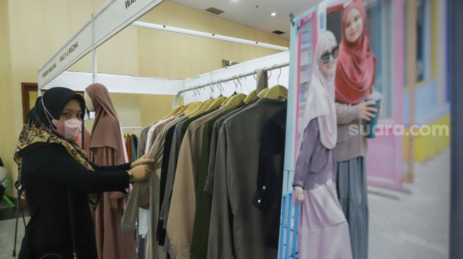 Pengunjung memilih pakaian di acara Muslima Festival 2021 di Smesco Indonesia, Jakarta Selatan, Sabtu (18/12/2021). [Suara.com/Alfian Winanto]