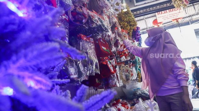 Pengunjung memilih barang pernak-pernik Natal di Pasar Asemka, Jakarta Barat, Sabtu (18/12/2021). [Suara.com/Alfian Winanto]