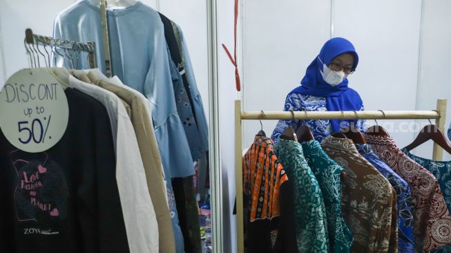 Pengunjung memilih pakaian di acara Muslima Festival 2021 di Smesco Indonesia, Jakarta Selatan, Sabtu (18/12/2021). [Suara.com/Alfian Winanto]