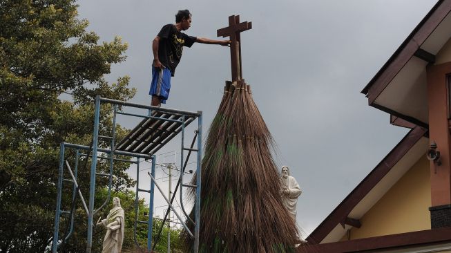 Petugas gereja memasang kayu salib saat membuat pohon Natal dari sapu lidi di Gereja Katolik Santa Perawan Maria Bunda Kristus, Wedi, Klaten, Jawa Tengah, Sabtu (18/12/2021).  ANTARA FOTO/Aloysius Jarot Nugroho
