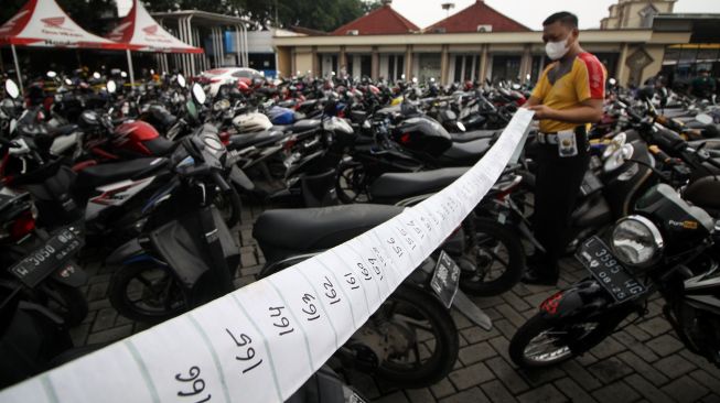 Petugas memasang nomer ratusan kendaraan bermotor milik warga yang terjaring razia di halaman Polresta Sidoarjo, Jawa Timur, Sabtu (18/12/2021). ANTARA FOTO/Umarul Faruq