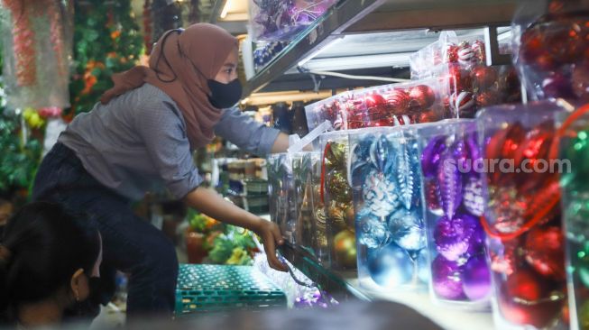 Pengunjung memilih barang pernak-pernik Natal di Pasar Asemka, Jakarta Barat, Sabtu (18/12/2021). [Suara.com/Alfian Winanto]