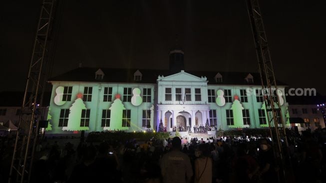 Sejumlah pengunjung melihat video mapping bernuansa Natal yang ditampilkan dalam acara 'Christmas in Jakarta' di Museum Fatahillah, Kota Tua, Jakarta, Minggu (19/12/2021). [Suara.com/Angga Budhiyanto]