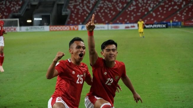 Bek sayap Timnas Indonesia, Pratama Arhan (kanan) merayakan golnya ke gawang Malaysia bersama penyerang sayap Irfan Jaya, dalam laga Piala AFF 2020 di National Stadium, Singapura, Minggu (19/12/2021) malam WIB. [dok. PSSI]