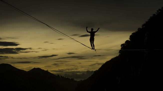 Pegiat olahraga ekstrem berjalan di atas tali webbing pada kegiatan Bandung Highlines Festival di Tebing Hawu, Kabupaten Bandung Barat, Sabtu (18/12/2021). [ANTARA FOTO/Novrian Arbi]