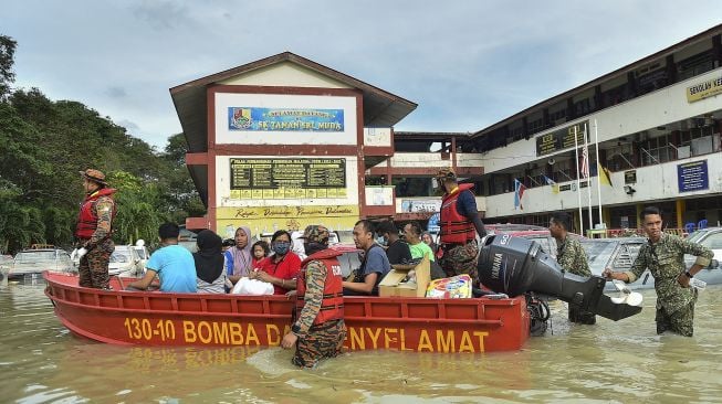 Petugas penyelamat mengevakuasi orang-orang yang terjebak banjir menggunakan perahu di Shah Alam, Selangor, Malaysia, Senin (20/12/2021). [ARIF KARTONO / AFP]