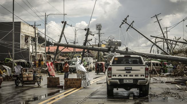 Tiang listrik jatuh memblokir jalan di Kota Surigao, Provinsi Surigao del Norte, Filipina, pada (19/12/2021). [FERDINANDH CABRERA / AFP]