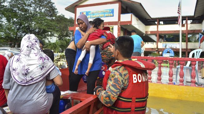 Petugas penyelamat mengevakuasi orang-orang yang terjebak banjir menggunakan perahu di Shah Alam, Selangor, Malaysia, Senin (20/12/2021). [ARIF KARTONO / AFP]