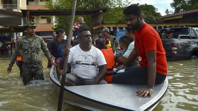 Petugas penyelamat mengevakuasi orang-orang yang terjebak banjir menggunakan perahu di Shah Alam, Selangor, Malaysia, Senin (20/12/2021). [ARIF KARTONO / AFP]