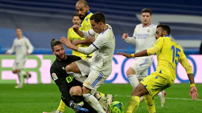 Aksi para pemain Cadiz menahan pergerakan penyerang Real Madrid, Eden Hazard. Kedua tim bertemu di Santiago Bernabeu dalam laga lanjutan La Liga, Senin (20/12/2021), hasilnya tanpa pemenang dengan skor akhir 0-0. (Foto: AFP)