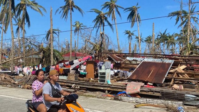 Warga melintasi wilayah yang porak-poranda diterjang Topan Rai di Filipina. (Foto: AFP)