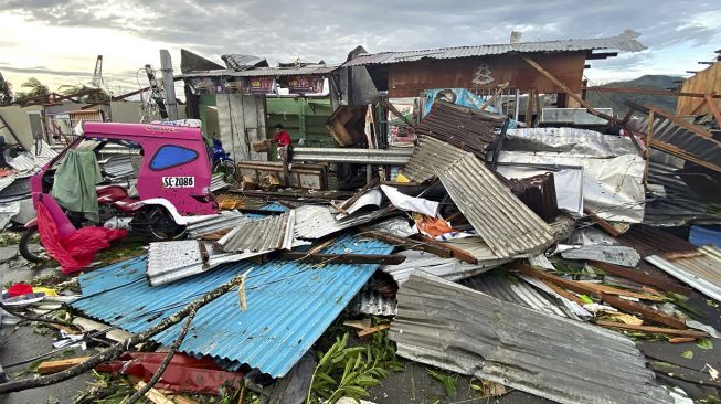 Seorang penduduk menyelamatkan barang-barang di antara puing-puing yang disebabkan oleh Topan Super Rai setelah badai melintasi Kota Surigao, Provinsi Surigao del Norte, Filipina, pada (17/12/2021). [ERWIN MASCARINAS / AFP]