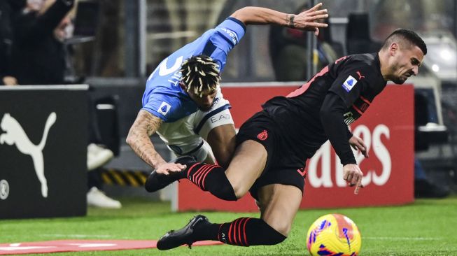 Bek Napoli Kevin Malcuit (kiri) dan gelandang AC Milan Rade Krunic bertabrakan selama pertandingan sepak bola Serie A Italia antara AC Milan dan Napoli di stadion San Siro, Milan, pada (19/12/2021). [MIGUEL MEDINA / AFP]