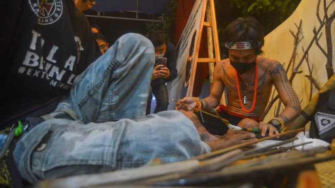 Seorang Sipatiti (seniman tato Mentawai), Alexander Kora Sakoddobat (kiri), mendemonstrasikan pembuatan tato tradisional Mentawai di Padang, Sumatera Barat, Senin (20/12/2021).  ANTARA FOTO/Iggoy el Fitra