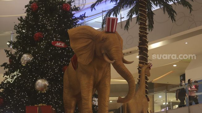 Pengunjung berjalan di dekat dekorasi Natal di Central Park Mall, Jakarta, Selasa (21/12/2021). [Suara.com/Angga Budhiyanto]