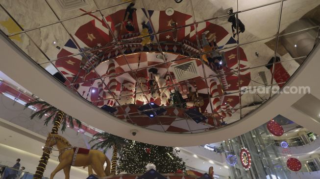 Refleksi sejumlah pengunjung berada di dekat dekorasi Natal di Central Park Mall, Jakarta, Selasa (21/12/2021). [Suara.com/Angga Budhiyanto]