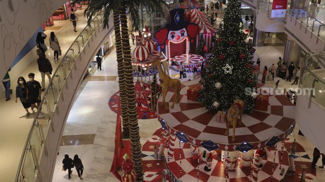 Pengunjung berjalan di dekat dekorasi Natal di Central Park Mall, Jakarta, Selasa (21/12/2021). [Suara.com/Angga Budhiyanto]