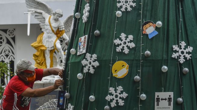 Umat Kristiani menghiasi pohon natal di Halaman Gereja Katolik Santo Yohanes, Kabupaten Ciamis, Jawa Barat, Selasa (21/12/2021).  ANTARA FOTO/Adeng Bustomi