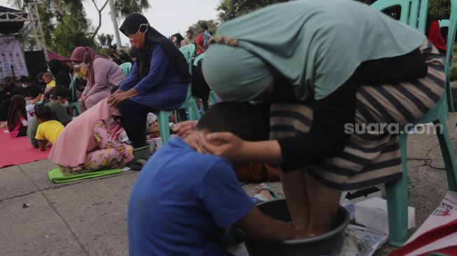 Sejumlah anak membasuh kaki ibunya saat acara Cuci Kaki Ibu Massal di Kelurahan Duri Pulo, Gambir, Jakarta, Rabu (22/12/2021). [Suara.com/Angga Budhiyanto]