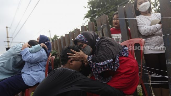 Dua orang ibu memeluk anaknya usai mengikuti acara Cuci Kaki Ibu Massal di Kelurahan Duri Pulo, Gambir, Jakarta, Rabu (22/12/2021). [Suara.com/Angga Budhiyanto]