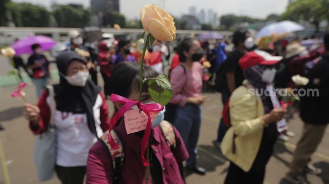 Massa yang tergabung dalam Jaringan Pembela Hak Perempuan Korban Kekerasan Seksual membawa bunga saat melakukan aksi unjuk rasa di depan Gedung DPR, Jakarta, Rabu (22/12/2021). [Suara.com/Angga Budhiyanto]