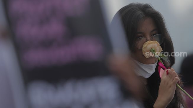 Massa yang tergabung dalam Jaringan Pembela Hak Perempuan Korban Kekerasan Seksual membawa bunga saat melakukan aksi unjuk rasa di depan Gedung DPR, Jakarta, Rabu (22/12/2021). [Suara.com/Angga Budhiyanto]