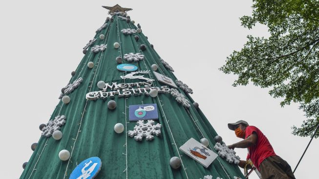 Umat Kristiani menghiasi pohon natal di Halaman Gereja Katolik Santo Yohanes, Kabupaten Ciamis, Jawa Barat, Selasa (21/12/2021).  ANTARA FOTO/Adeng Bustomi