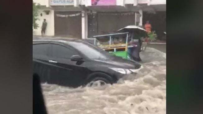 Melaju Kencang saat Banjir, Mobil Ini Bikin Tukang Sayur Beserta Gerobaknya Terjungkal