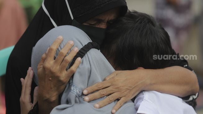 Seorang ibu memeluk anaknya usai mengikuti acara Cuci Kaki Ibu Massal di Kelurahan Duri Pulo, Gambir, Jakarta, Rabu (22/12/2021). [Suara.com/Angga Budhiyanto]