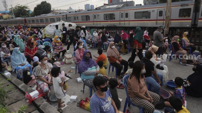 Sejumlah ibu dan anak bersiap mengikuti acara Cuci Kaki Ibu Massal di Kelurahan Duri Pulo, Gambir, Jakarta, Rabu (22/12/2021). [Suara.com/Angga Budhiyanto]