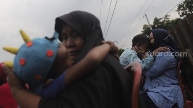 Dua orang ibu memeluk anaknya usai mengikuti acara Cuci Kaki Ibu Massal di Kelurahan Duri Pulo, Gambir, Jakarta, Rabu (22/12/2021). [Suara.com/Angga Budhiyanto]