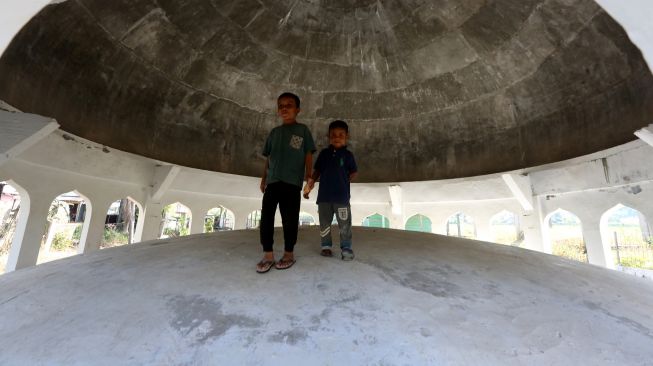 Dua orang bocah bermain di dalam kubah masjid yang terdampar akibat hanyut terbawa gelombang tsunami 26 Desember 2004 di Desa Gurah, Aceh Besar, Aceh, Kamis (23/12/2021). ANTARA FOTO/Irwansyah Putra