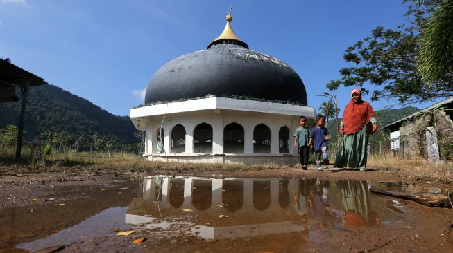 Warga melintas di samping kubah masjid yang terdampar akibat hanyut terbawa gelombang tsunami 26 Desember 2004 di Desa Gurah, Aceh Besar, Aceh, Kamis (23/12/2021).  ANTARA FOTO/Irwansyah Putra