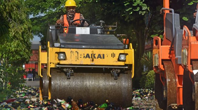 Petugas mengoperasikan alat berat saat pemusnahan ribuan botol minuman keras (miras) ilegal di Serang, Banten, Kamis (23/12/2021). ANTARA FOTO/Asep Fathulrahman