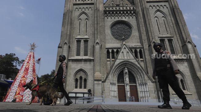 Personel kepolisian berjaga di depan Gereja Katedral, Jakarta, Jumat (24/12/2021). [Suara.com/Angga Budhiyanto]