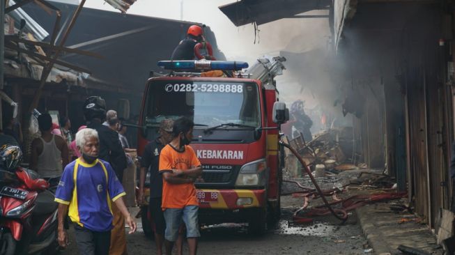 Petugas pemadam kebakaran masih melakukan pendinginan di titik api yang membakar Pasar Induk Kroya, Kabupaten Cilacap, Jumat (24/12/2021). [Suara.com/Anang Firmansyah]