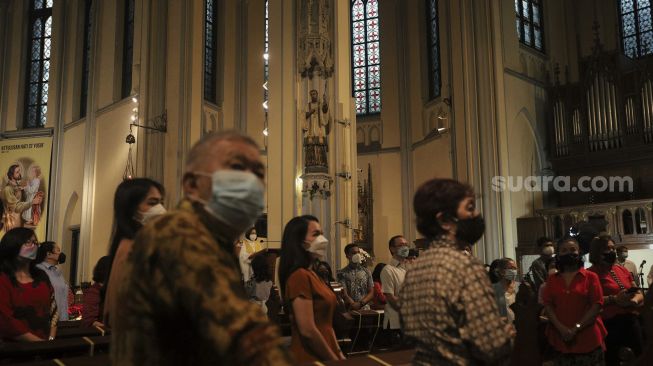 Umat Kristiani mengikuti Misa Natal di Gereja Katedral, Jakarta, Jumat (24/12/2021). [Suara.com/Angga Budhiyanto]