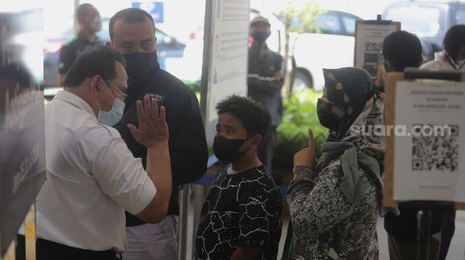 Petugas memberi arahan kepada calon penumpang yang akan melakukan tes usap antigen dan PCR di Stasiun Pasar Senen, Jakarta, Jumat (24/12/2021). [Suara.com/Angga Budhiyanto]