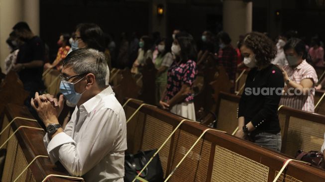 Umat Kristiani memanjatkan doa saat mengikuti Misa Natal di Gereja Katedral, Jakarta, Jumat (24/12/2021). [Suara.com/Angga Budhiyanto]