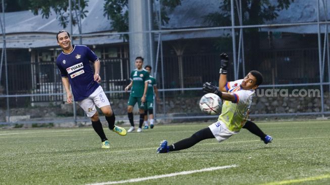 Aksi Presenter Billy Syahputra ketika mencetak gol ke gawang lawan saat laga persahabatan antara Selebritis FC vs AIFC Garuda Putih di Lapangan ABC Senayan, Jakarta Pusat, Jumat (24/12/2021). [Suara.com/Alfian Winanto]