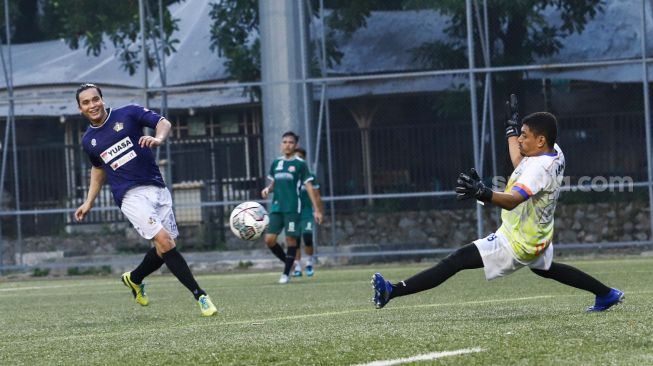 Aksi Presenter Billy Syahputra ketika mencetak gol ke gawang lawan saat laga persahabatan antara Selebritis FC vs AIFC Garuda Putih di Lapangan ABC Senayan, Jakarta Pusat, Jumat (24/12/2021). [Suara.com/Alfian Winanto]