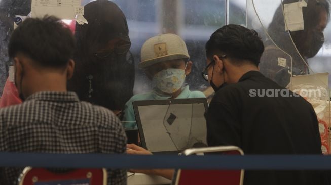 Orang tua mendaftarkan anaknya untuk melakukan tes usap PCR di Stasiun Pasar Senen, Jakarta, Jumat (24/12/2021). [Suara.com/Angga Budhiyanto]