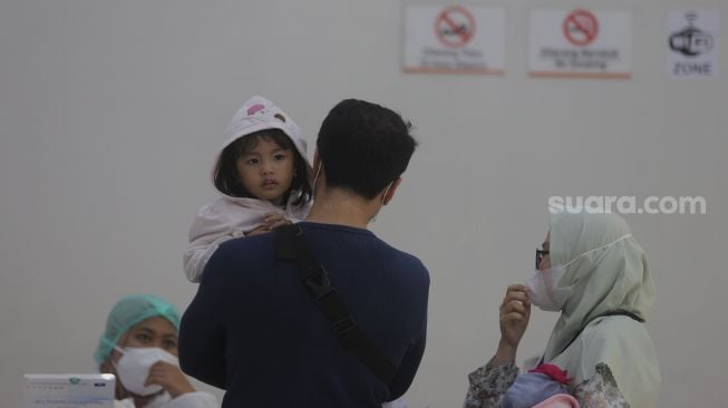 Orang tua mendaftarkan anaknya untuk melakukan tes usap PCR di Stasiun Pasar Senen, Jakarta, Jumat (24/12/2021). [Suara.com/Angga Budhiyanto]