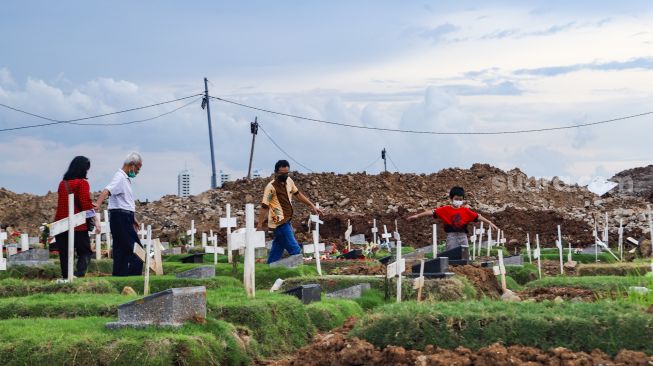 Warga datang untuk ziarah di makam keluarganya di TPU Rorotan, Jakarta Utara, Sabtu (25/12/2021). [Suara.com/Alfian Winanto]