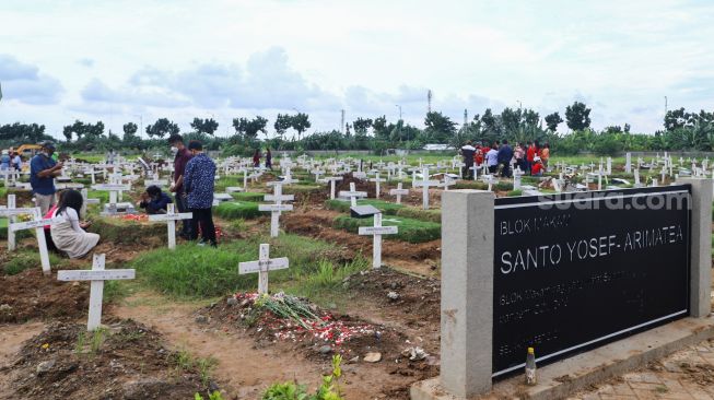 Suasana warga berziarah di TPU Rorotan, Jakarta Utara, Sabtu (25/12/2021). [Suara.com/Alfian Winanto]