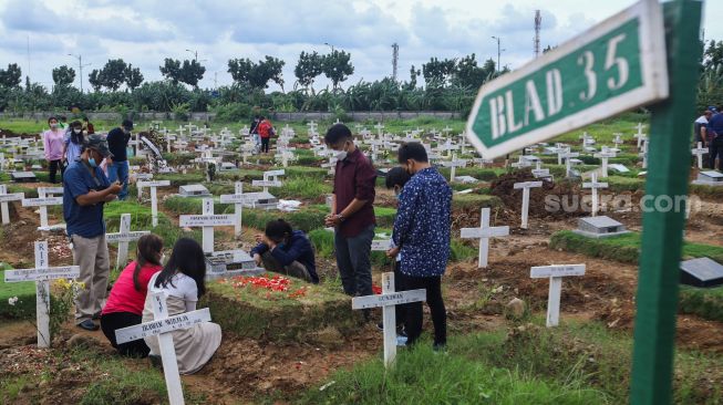 Warga ziarah di makam keluarganya di TPU Rorotan, Jakarta Utara, Sabtu (25/12/2021). [Suara.com/Alfian Winanto]